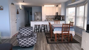 Een moderne keuken met witte kasten, een roestvrijstalen koelkast en een eethoek met een tafel en stoelen.