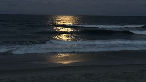 Een strand met golven en een nachtelijke hemel.