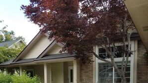 A house with a covered porch, a brick exterior, and a well-maintained garden with various plants and flowers. - Eagle ~ Great Sky Neighborhood ~ 4-Bdrms  ~ Near Pool & Shopping ~ ALL Amenities (Eagle)