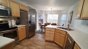 A kitchen with wooden cabinets, a stainless steel refrigerator, a microwave, and an oven. - Eagle ~ Great Sky Neighborhood ~ 4-Bdrms  ~ Near Pool & Shopping ~ ALL Amenities (Eagle)