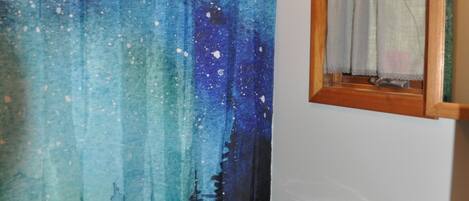 A bathroom with a starry night shower curtain, a wooden toilet, and a wooden cabinet.