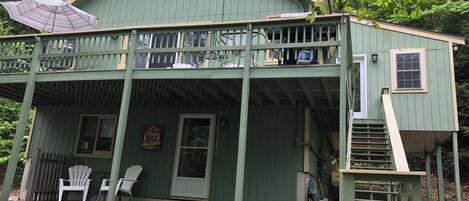 Une maison en bois peinte en vert, dotée d’un balcon, d’un porche et d’une porte d’entrée.