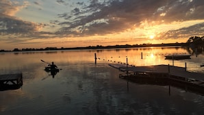 Um lago tranquilo ao pôr do sol, com um píer e um caiaque.