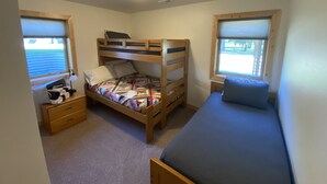 Quarto com beliches, escrivaninha e janela.
