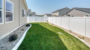 Un quartier résidentiel caractérisé par une pelouse bien entretenue, des clôtures blanches et des maisons présentant des styles architecturaux similaires.
