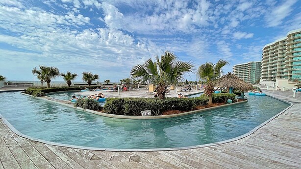 A pool area with a wooden deck, palm trees, and lounge chairs. - PENTHOUSE DPH14:  3BR/3BA Sleeps 8 Amazing views and amenities (Orange Beach)