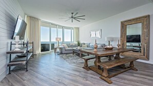 A spacious living room with a large wooden dining table, a sofa set, and a large mirror. - PENTHOUSE DPH14:  3BR/3BA Sleeps 8 Amazing views and amenities (Orange Beach)