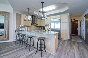 Uma cozinha moderna com uma ilha central, banquetas e eletrodomésticos de aço inoxidável.