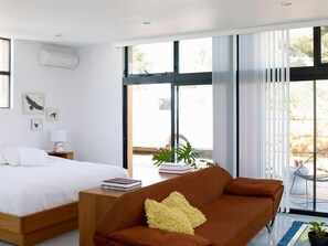 Relax in this serene bedroom with a large bed against a window, a sofa, and a reading nook.