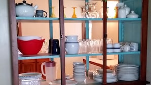 Ein Holzschrank mit Glastüren, der verschiedene Küchenutensilien und Dekorationsobjekte beherbergt.