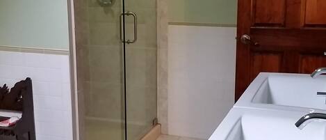 A bathroom with a shower, a sink, and a wooden door.