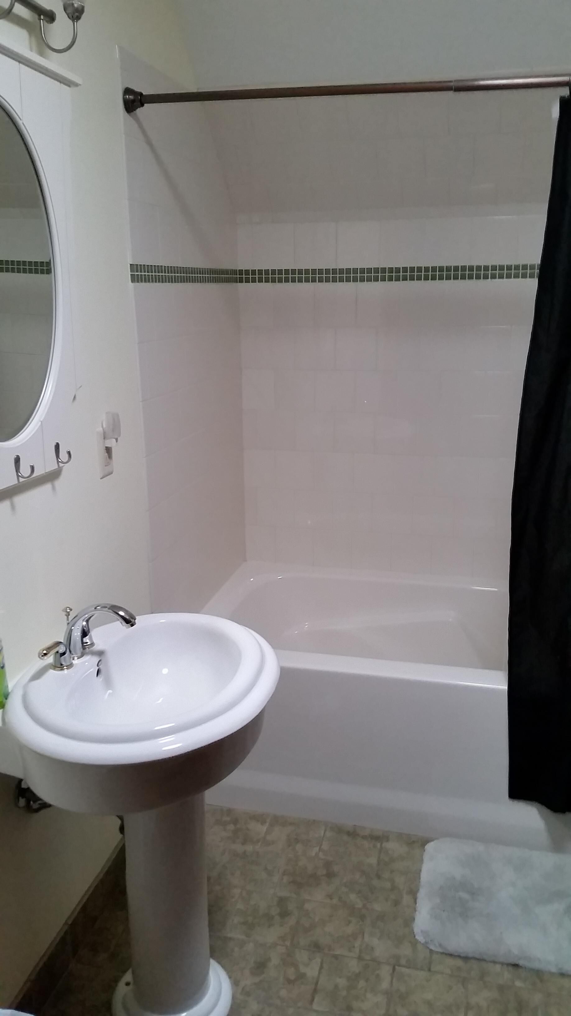 A bathroom with a pedestal sink, a bathtub, and a shower curtain.