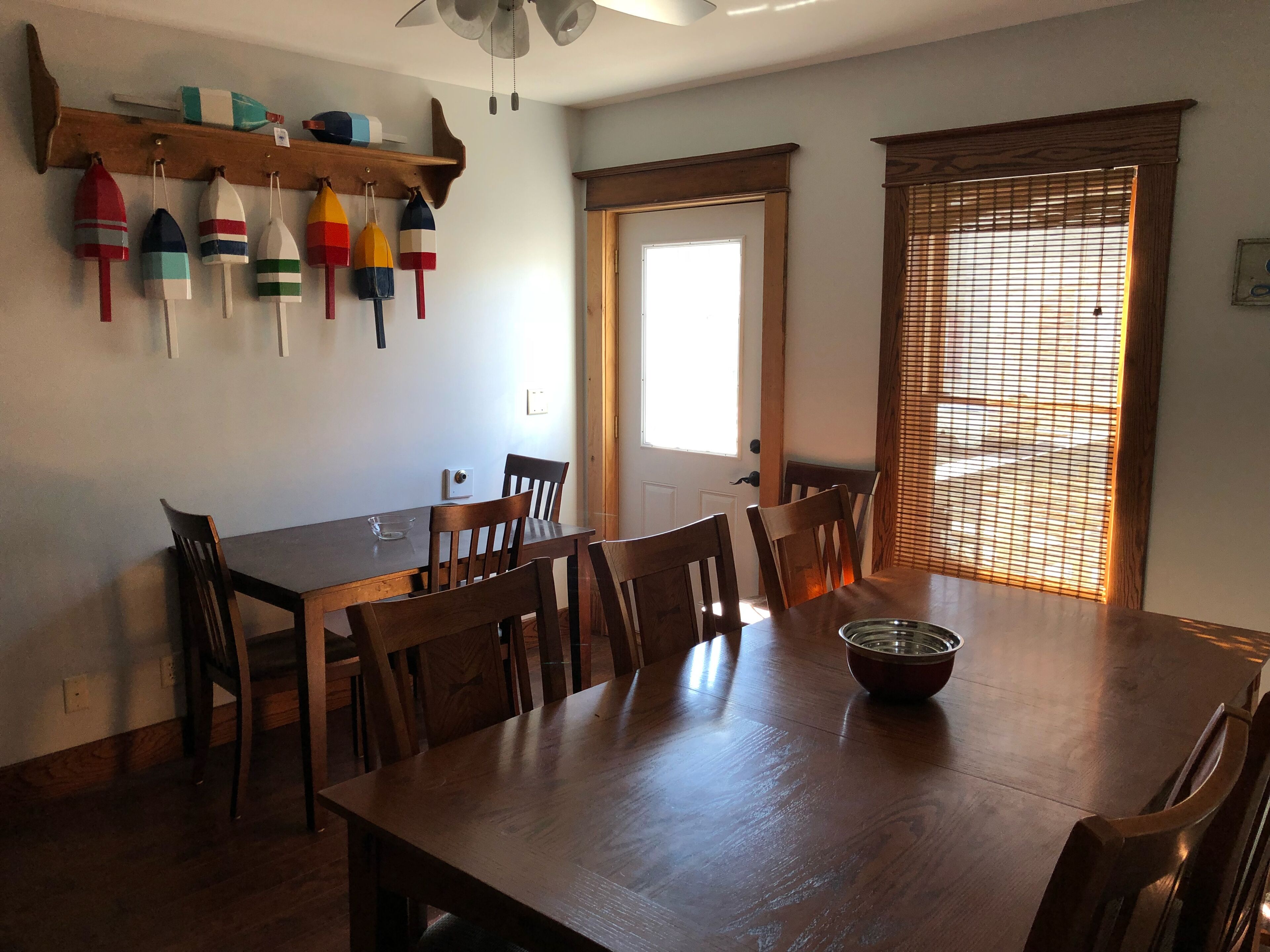 A dining area with a wooden table, six chairs, a ceiling fan, and a window with blinds.