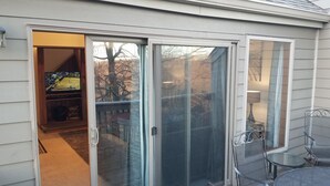 Une porte-fenêtre coulissante donnant sur une terrasse aménagée avec du mobilier d’extérieur.