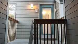 Une maison avec un porche, une porte avec une plaque de numéro et un luminaire au-dessus de la porte.