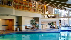 A large indoor swimming pool with a second-floor balcony, lounge chairs, and potted plants. - LUXURIOUS AND SPACIOUS CONDO ,SKI IN/ SKI OUT IN BEAVER CREEK, COLORADO. (Avon)