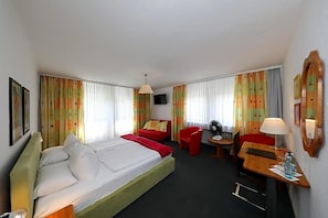 A hotel room with a bed, a desk, a chair, a TV, and curtains.
