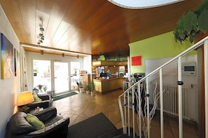 Eine Hotelhalle mit einer Rezeption, einer Treppe und einer Sitzecke mit Sofa und Lampe.