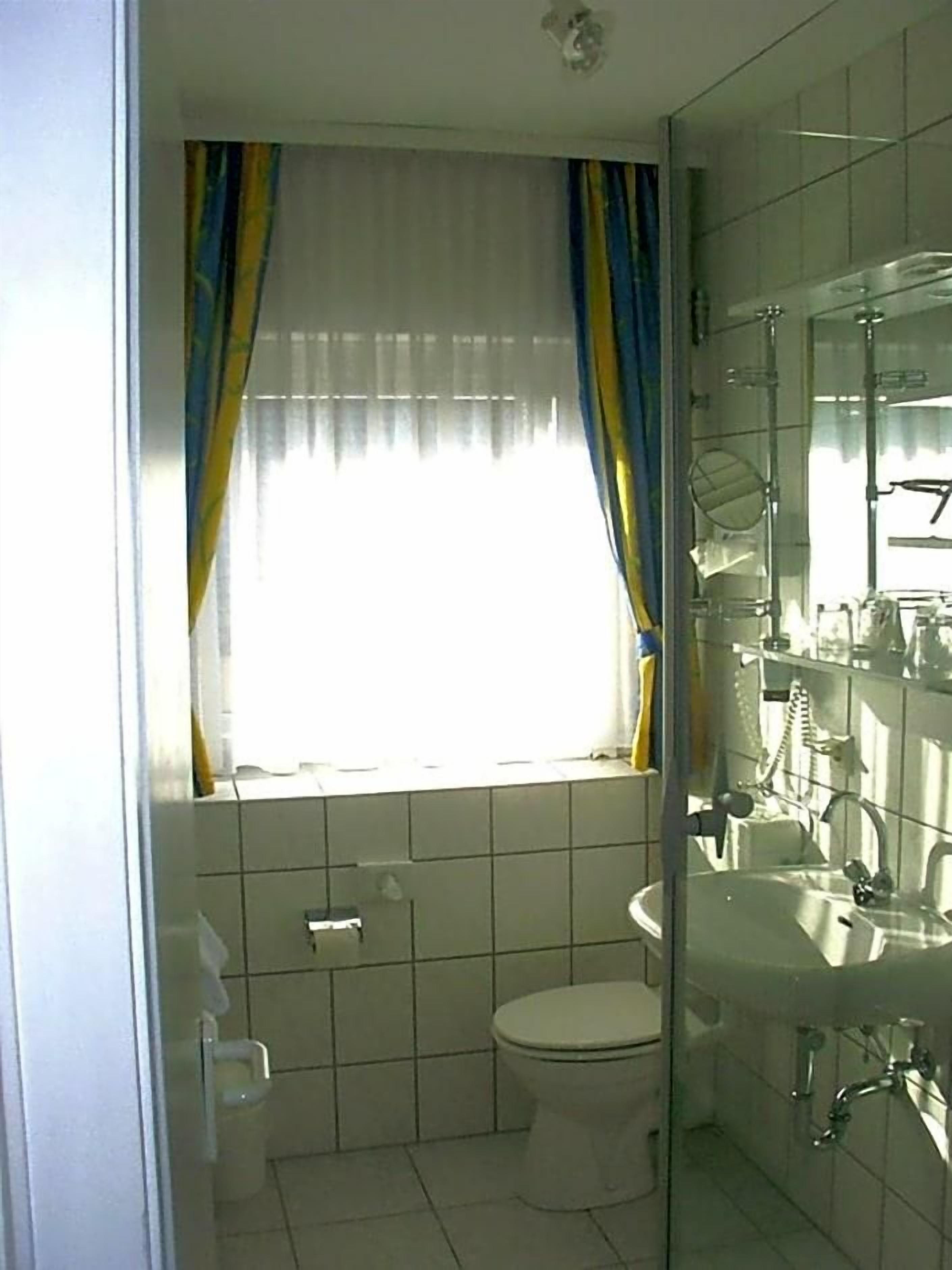 Une salle de bain comprenant des toilettes, un lavabo et un espace douche.