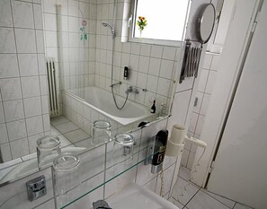 Ein Badezimmer mit Duschkabine aus Glas, einer Badewanne und einem Waschbecken aus Glas mit Stauraum in Gläsern.