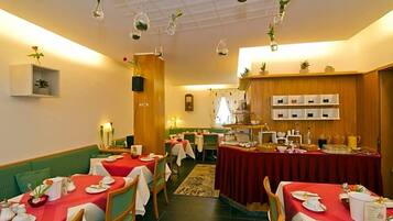 Ein Essbereich mit gedeckten Tischen, ein Buffet mit verschiedenen Speisen und hängenden Pflanzen.