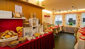 Ein reichhaltiges Buffet mit verschiedenen Speisen und ein Essbereich mit Tischen und Stühlen.