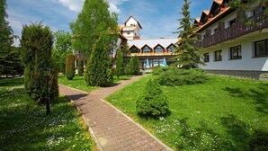 A traditional building with a central courtyard, surrounded by well-maintained greenery and a paved walkway. - Geovita Zlockie (Muszyna)