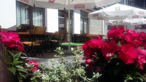 An outdoor seating area with tables and chairs, surrounded by potted plants and flowers. - Geovita Zlockie (Muszyna)