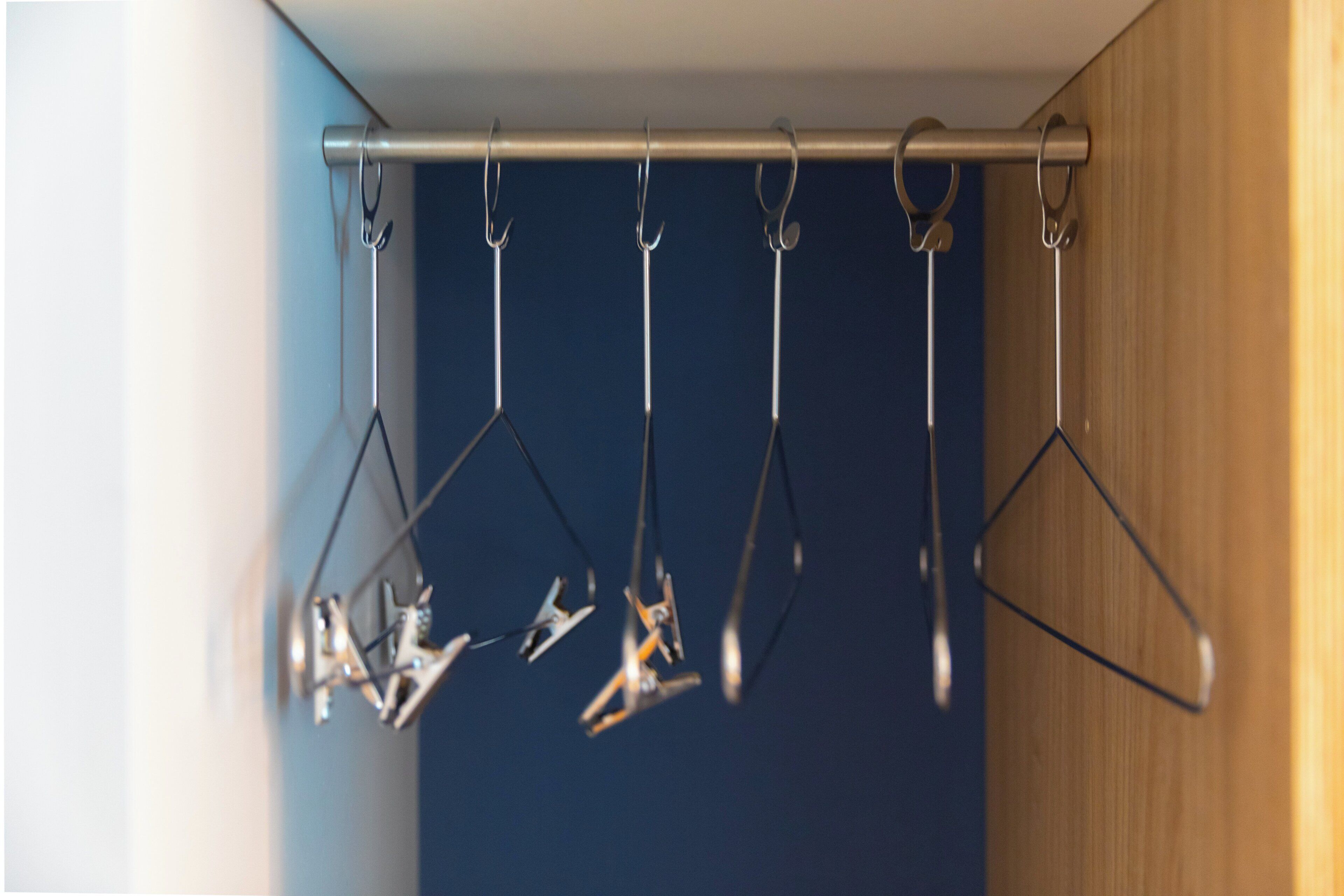 A metal rod with multiple hooks against a wall.
