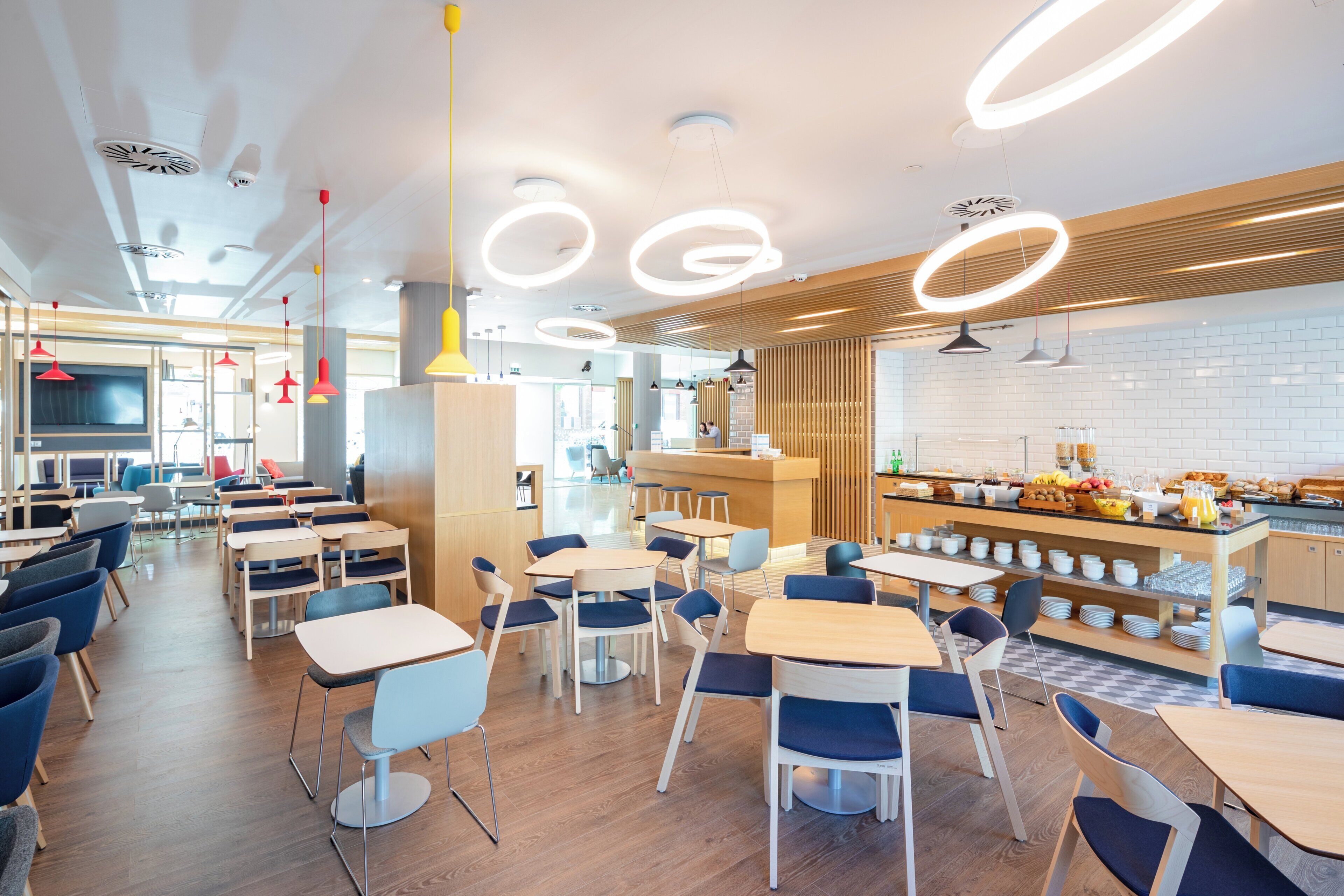 A modern cafe with round tables and chairs, a breakfast bar, and a view of the street.