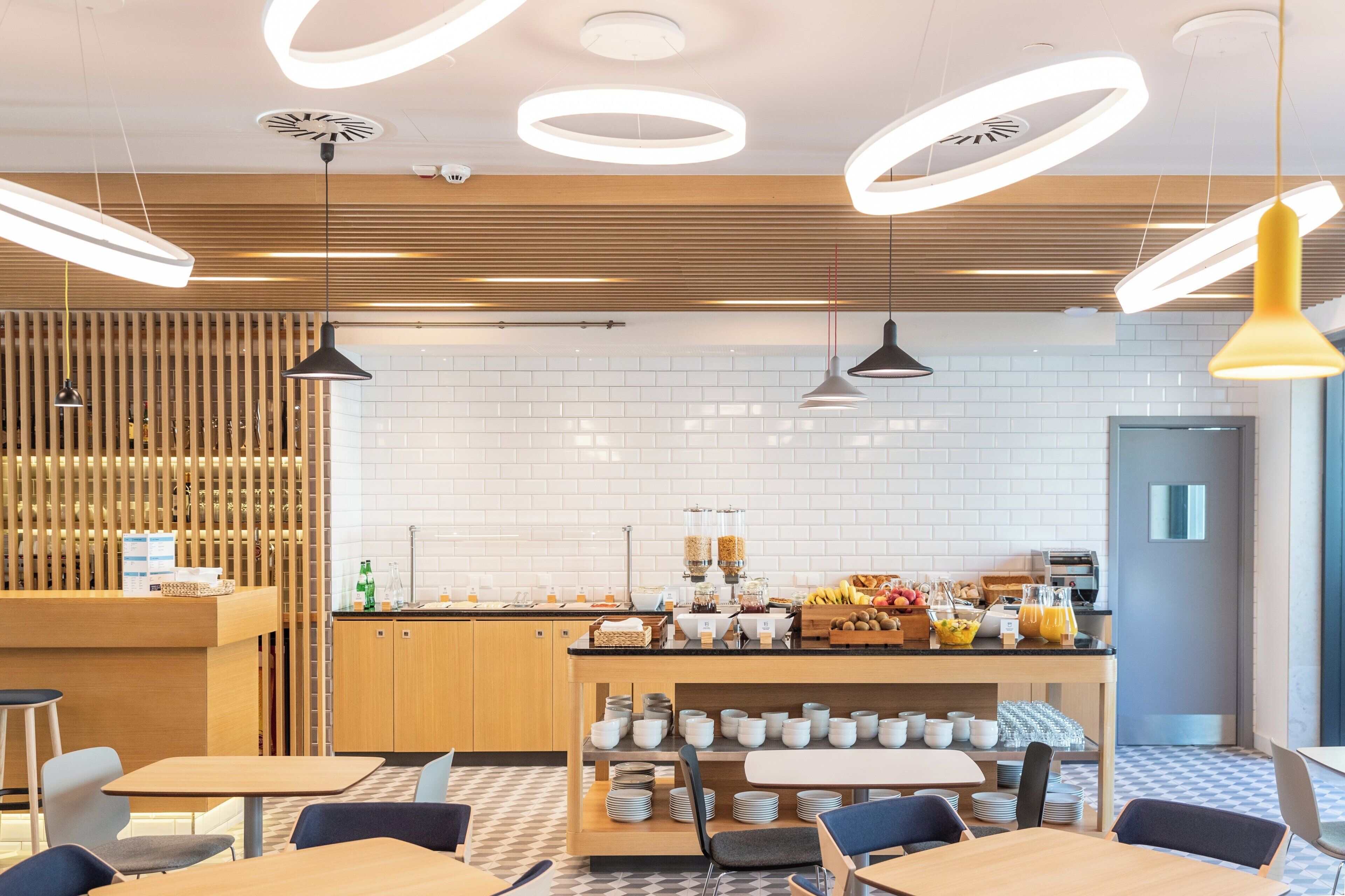 A modern cafe with a central counter, seating area, and a variety of breakfast items.