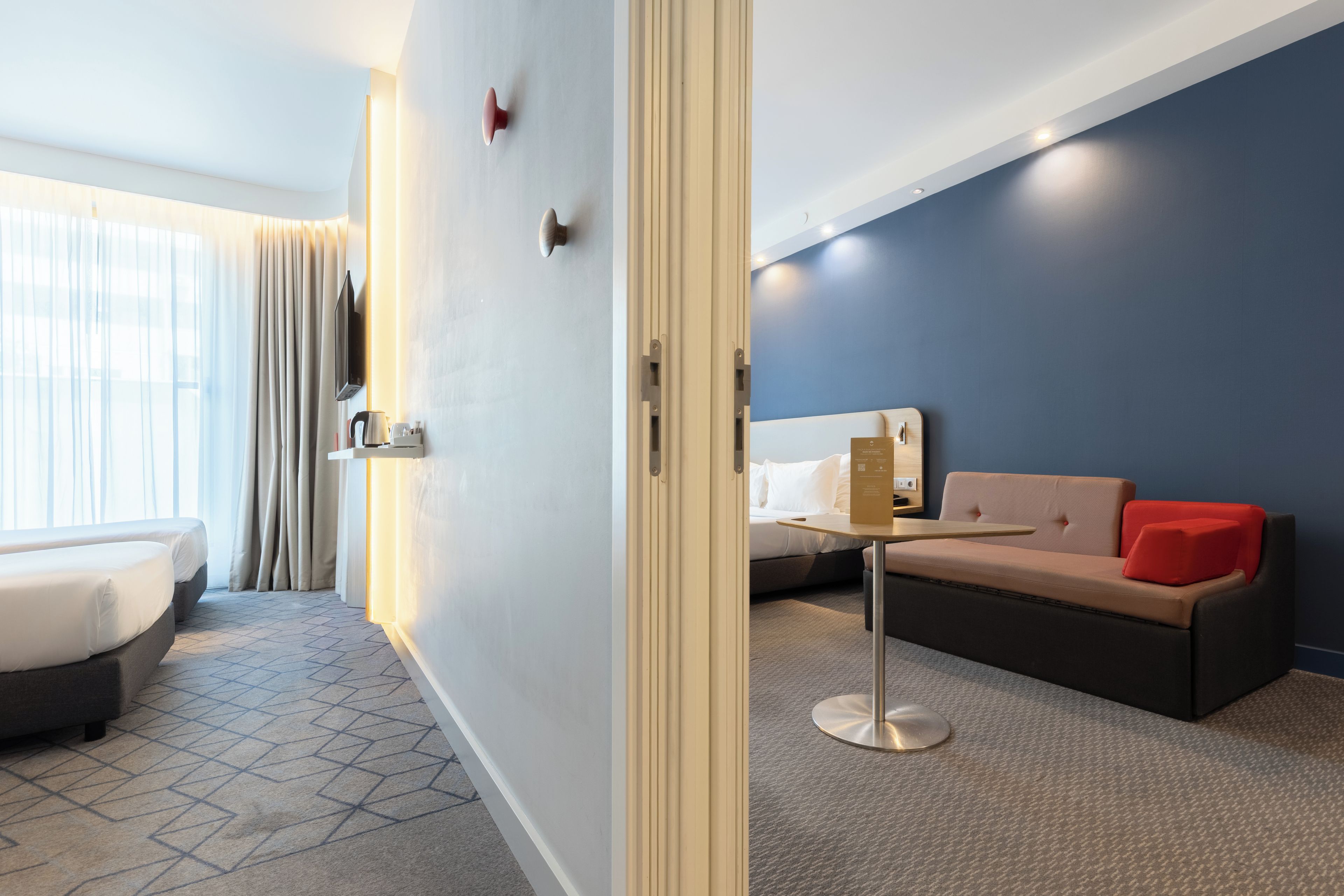 A hotel room with a bed, a sofa, a small table, and a TV.