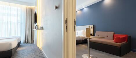 A hotel room with a bed, a sofa, a small table, and a TV.