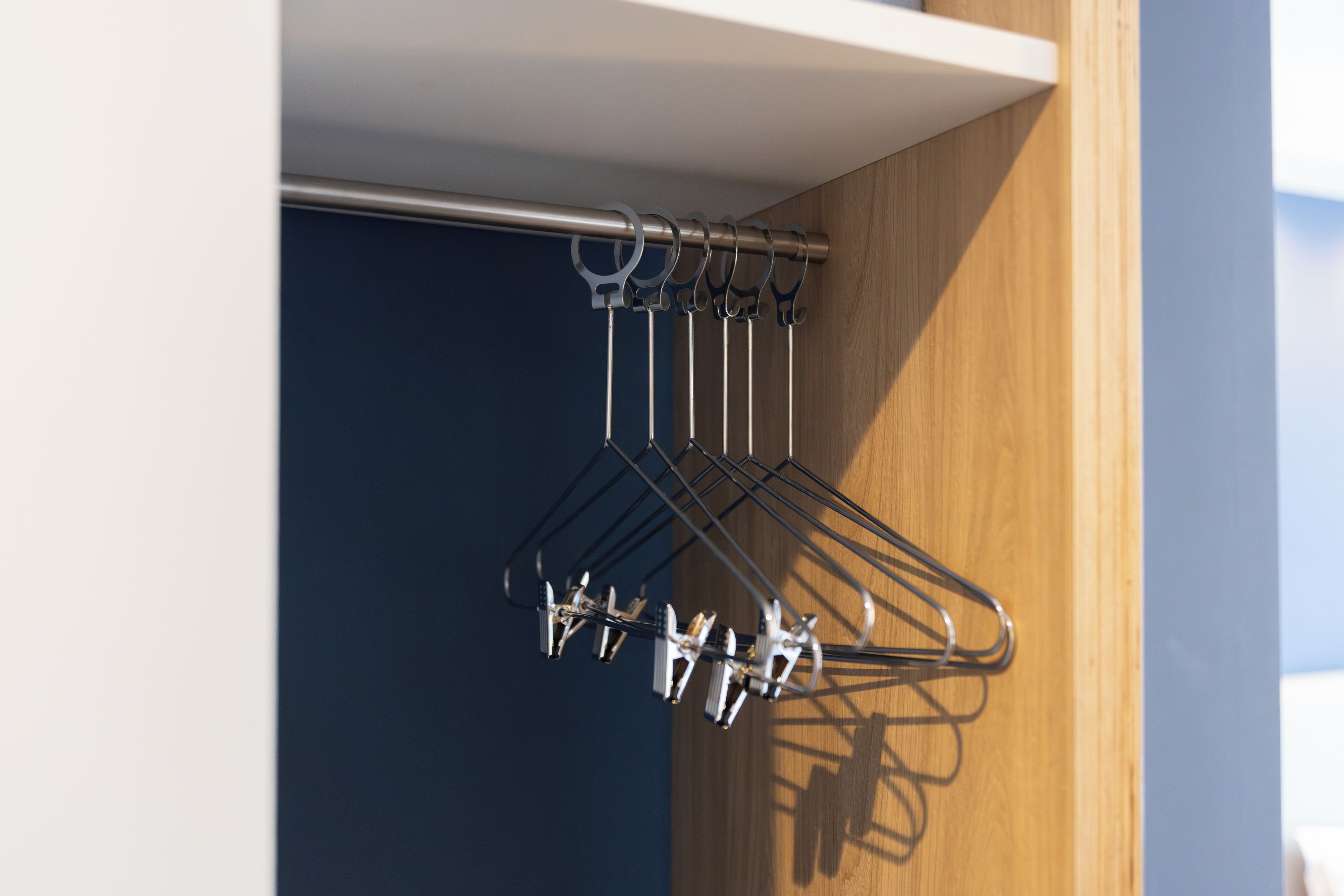 Een metalen droogrek met meerdere haken tegen een houten wand.