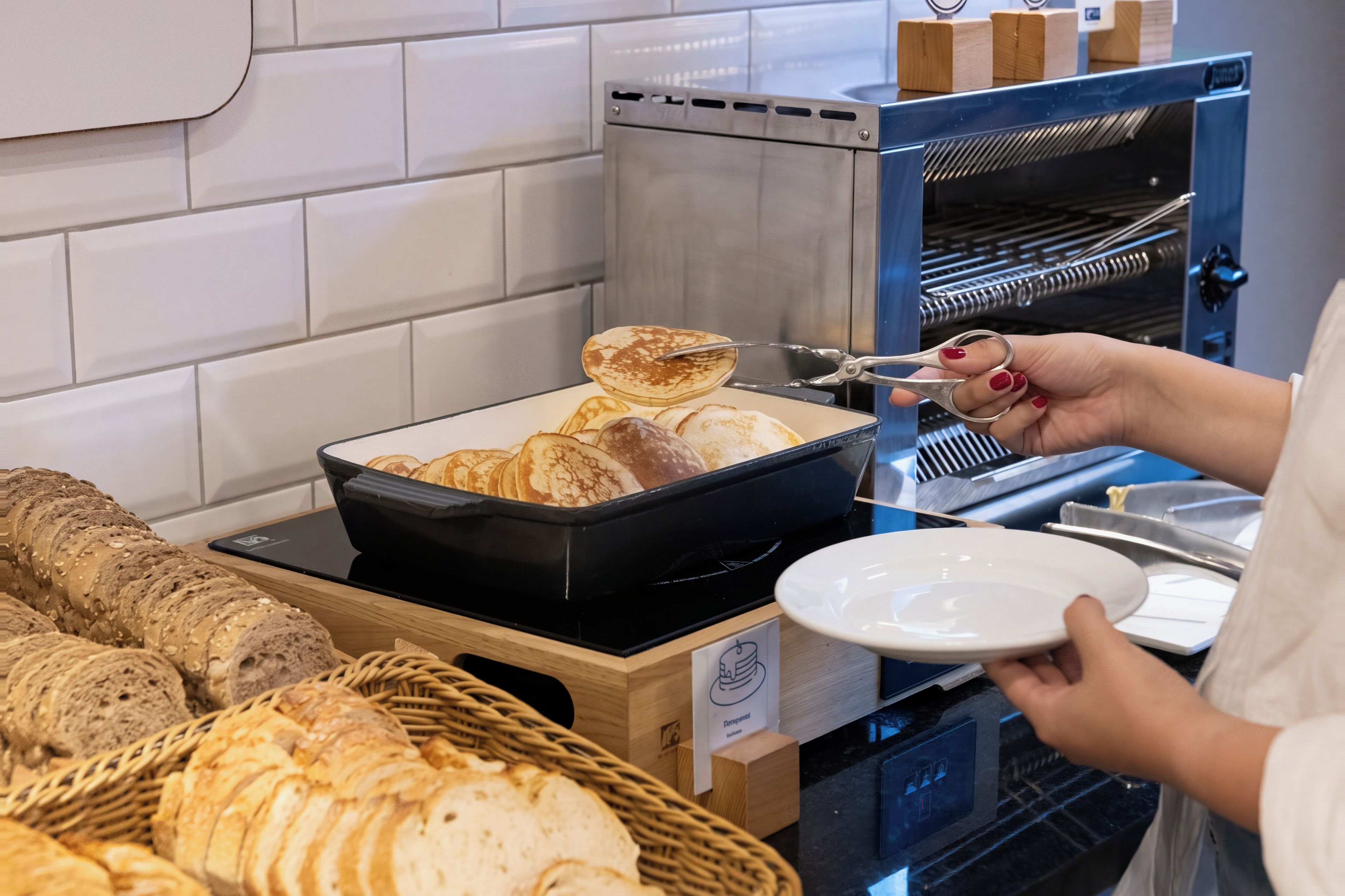 A buffet setup with bread, a toaster, and a person serving food.