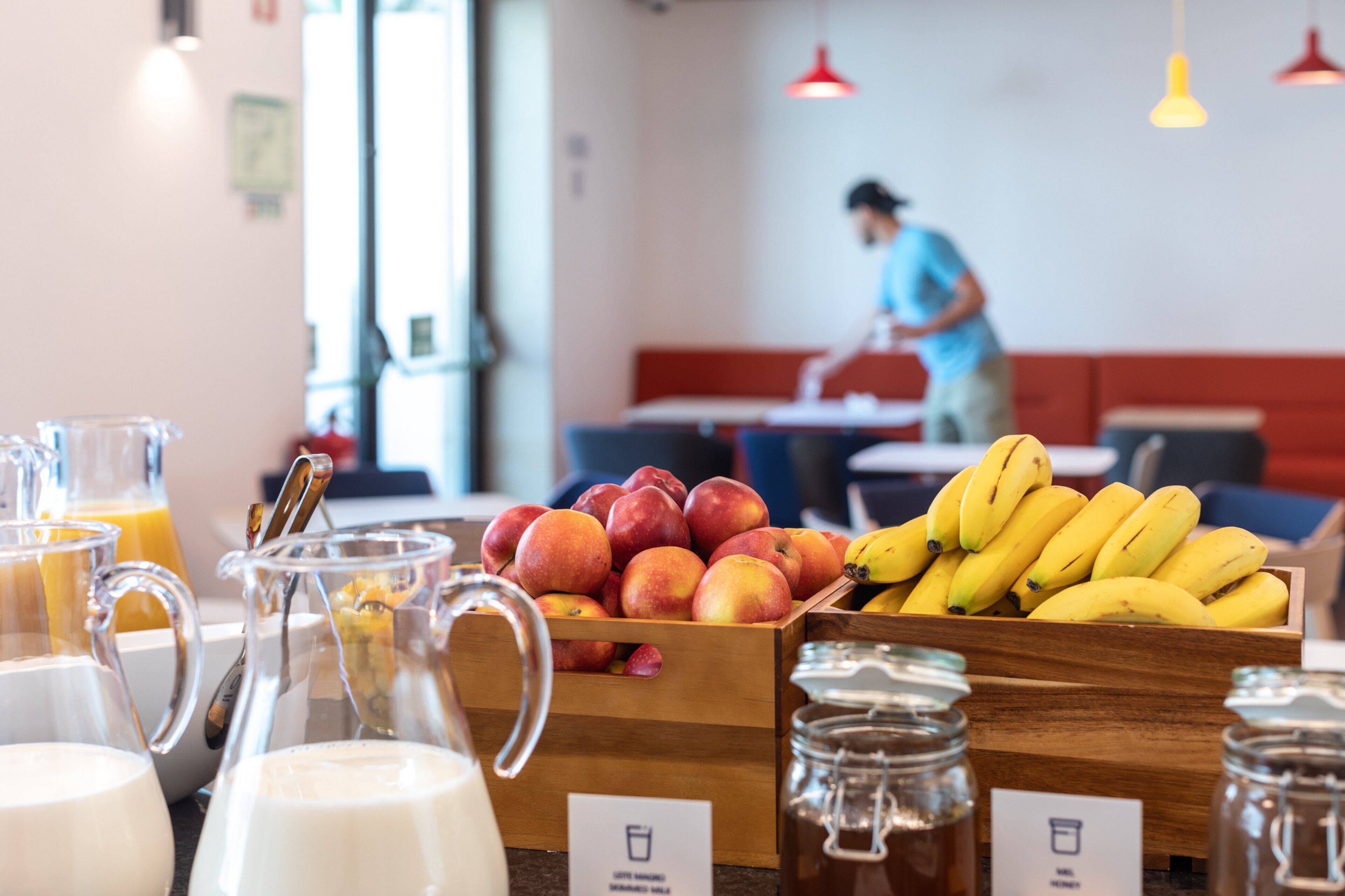 A breakfast buffet with fruits, beverages, and a person in the background.