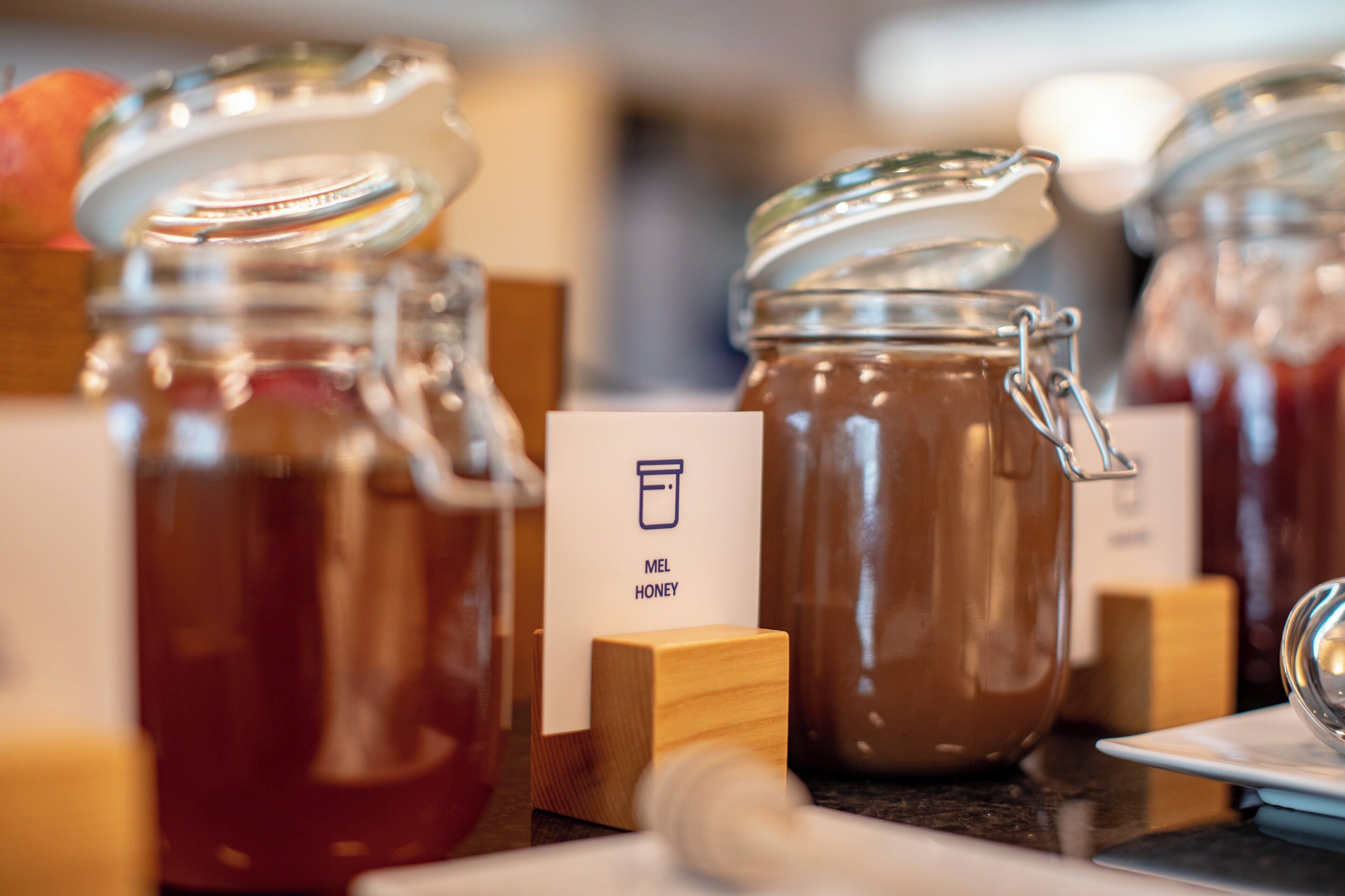 A display of honey jars with wooden labels, one labeled 'MEL HONEY'.
