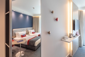 Ein Hotelzimmer mit Bett, Nachttisch und einem flachbildfernseher an der Wand.