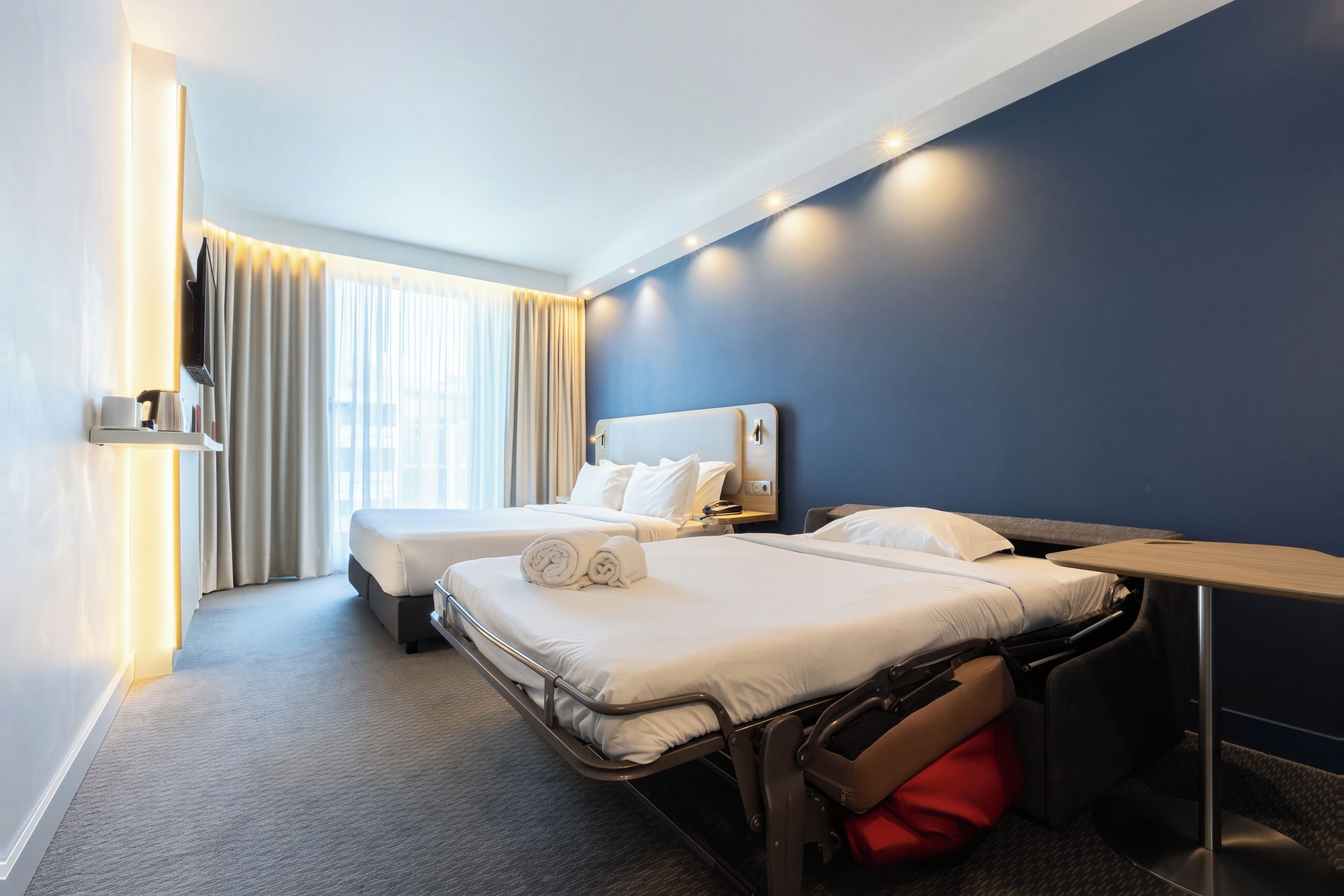 A hotel room with two beds, a desk, and a chair.