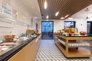 Un área de desayuno moderna con diversas opciones de alimentos y un piso de baldosas geométricas y limpias.
