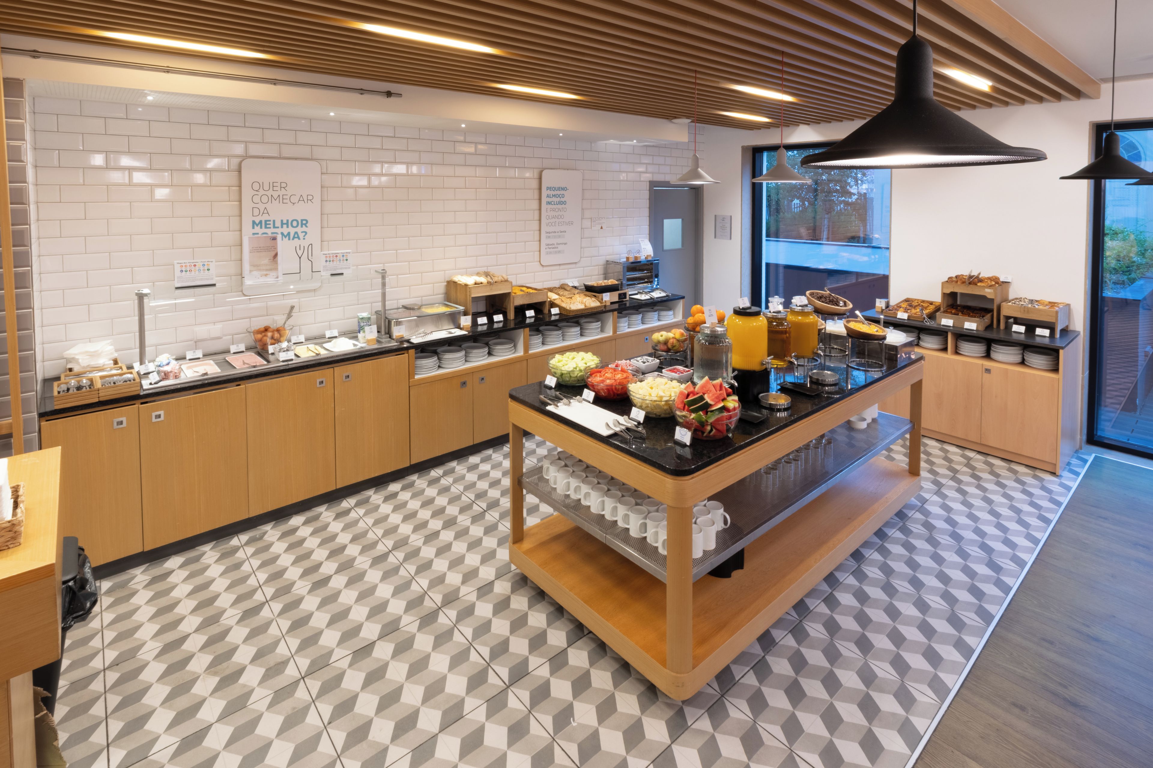 Ein modernes Frühstücksbuffet mit vielfältigen Speisen und einem hellen, geometrisch gemusterten Fliesenboden.