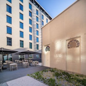Ein Hotelinnenhof mit Sitzgelegenheiten im Freien und einem großen Gebäude mit vielen Fenstern.