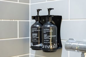 Twee zwarte flessen Urban Skincare producten op een betegelde muur.