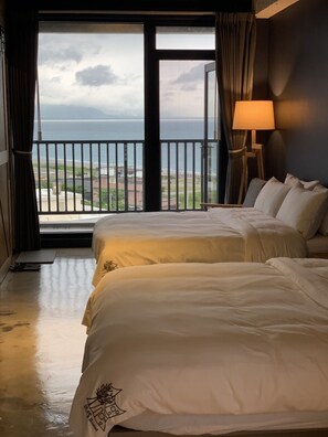 A hotel room with two beds, a view of the sea, and a lamp. - Comesit (Xincheng)