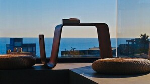 A modern chair with a curved backrest and a smartphone on a windowsill, overlooking a coastal view. - Comesit (Xincheng)