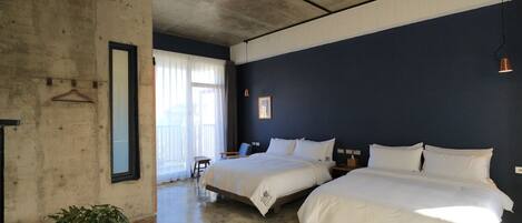 Habitación de hotel con dos camas, una planta en maceta y un ventanal con cortinas.