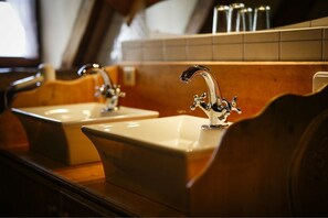 Ein Badezimmer mit zwei Waschbecken, jeweils mit einem modernen Wasserhahn, und einer Holzauslage.