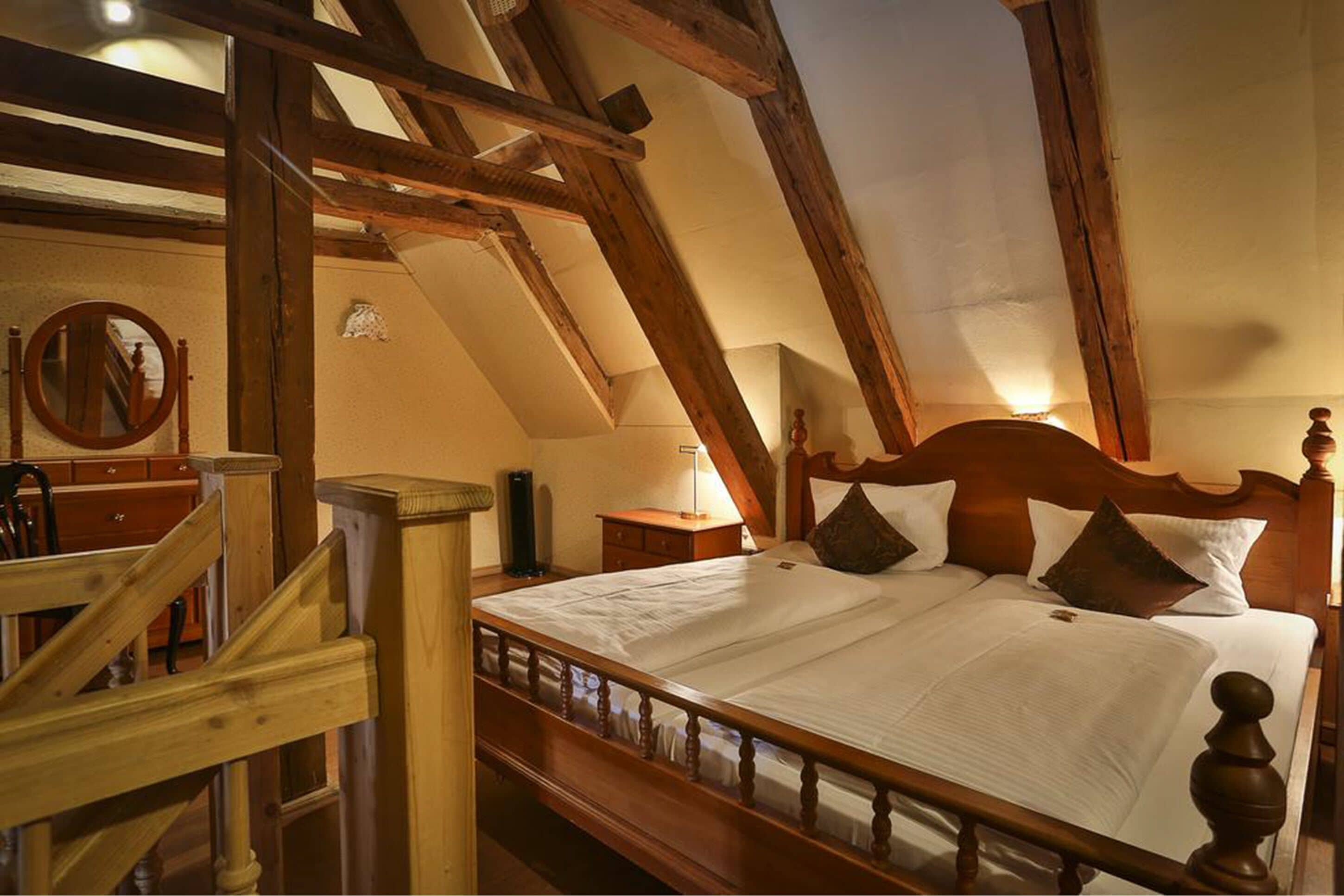 Un dormitorio con una cama de madera, una mesita de noche, una lámpara y una escalera de madera.