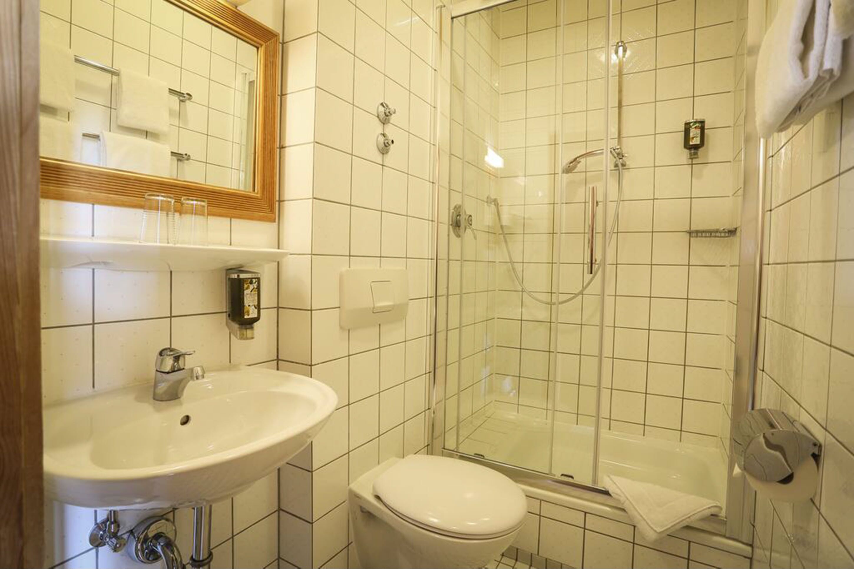 A bathroom with a sink, toilet, and glass-enclosed shower.