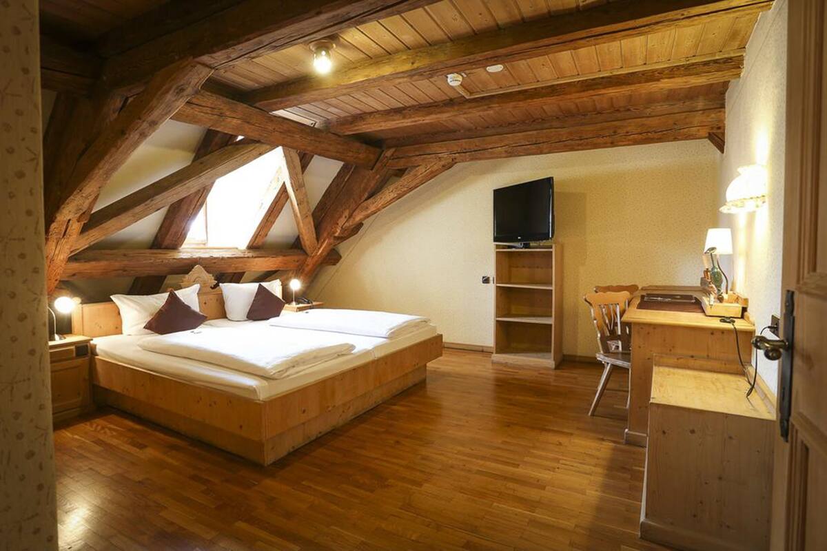 Un dormitorio con techo de madera, una cama, un escritorio y un televisor.